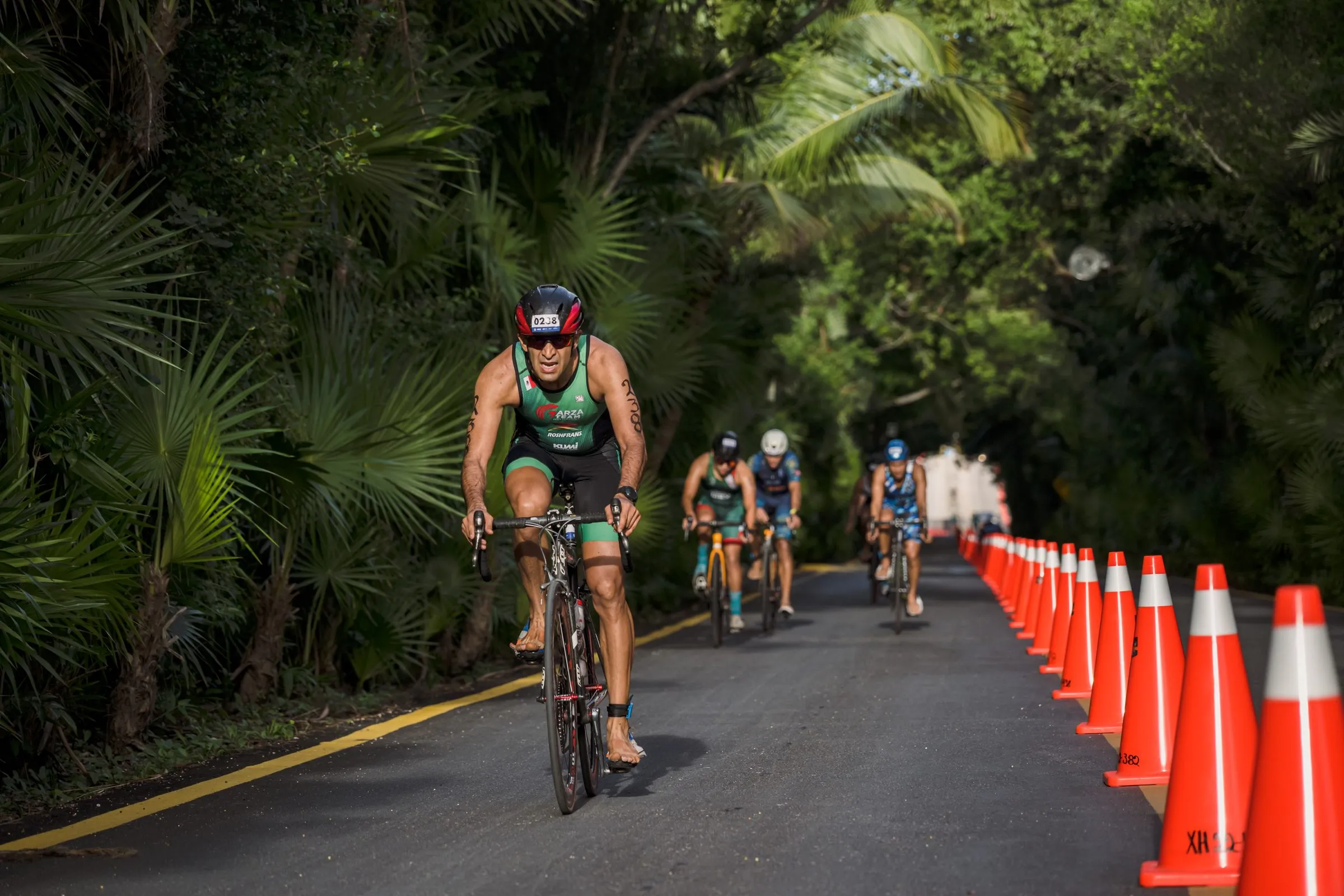 Ciclistas pasando por un punto fijo de cámara delimitado con conos en la ruta del triatlón