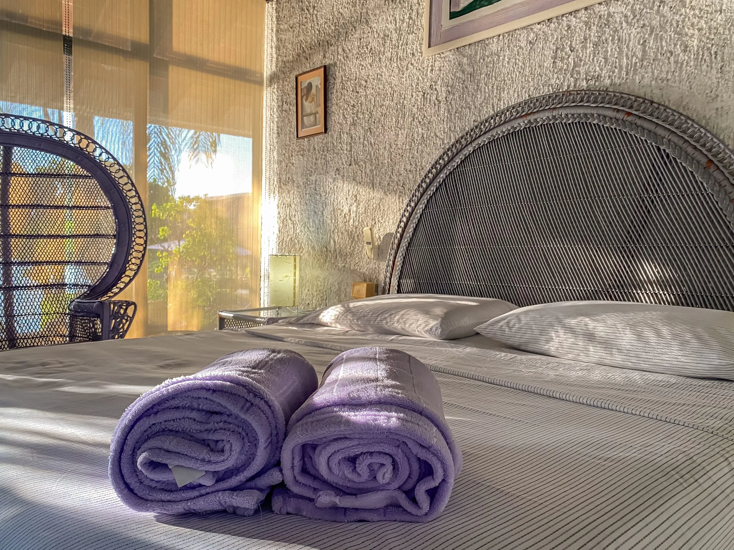 Hotel bedroom styled with rolled towels and decor accents, photographed to a defined brand style