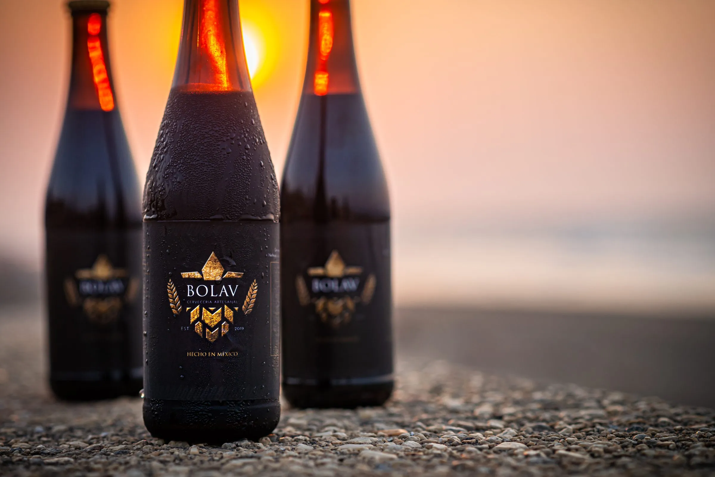Botellas de cerveza Bolav en fila con reflejos controlados, técnica de iluminación para producto de vidrio