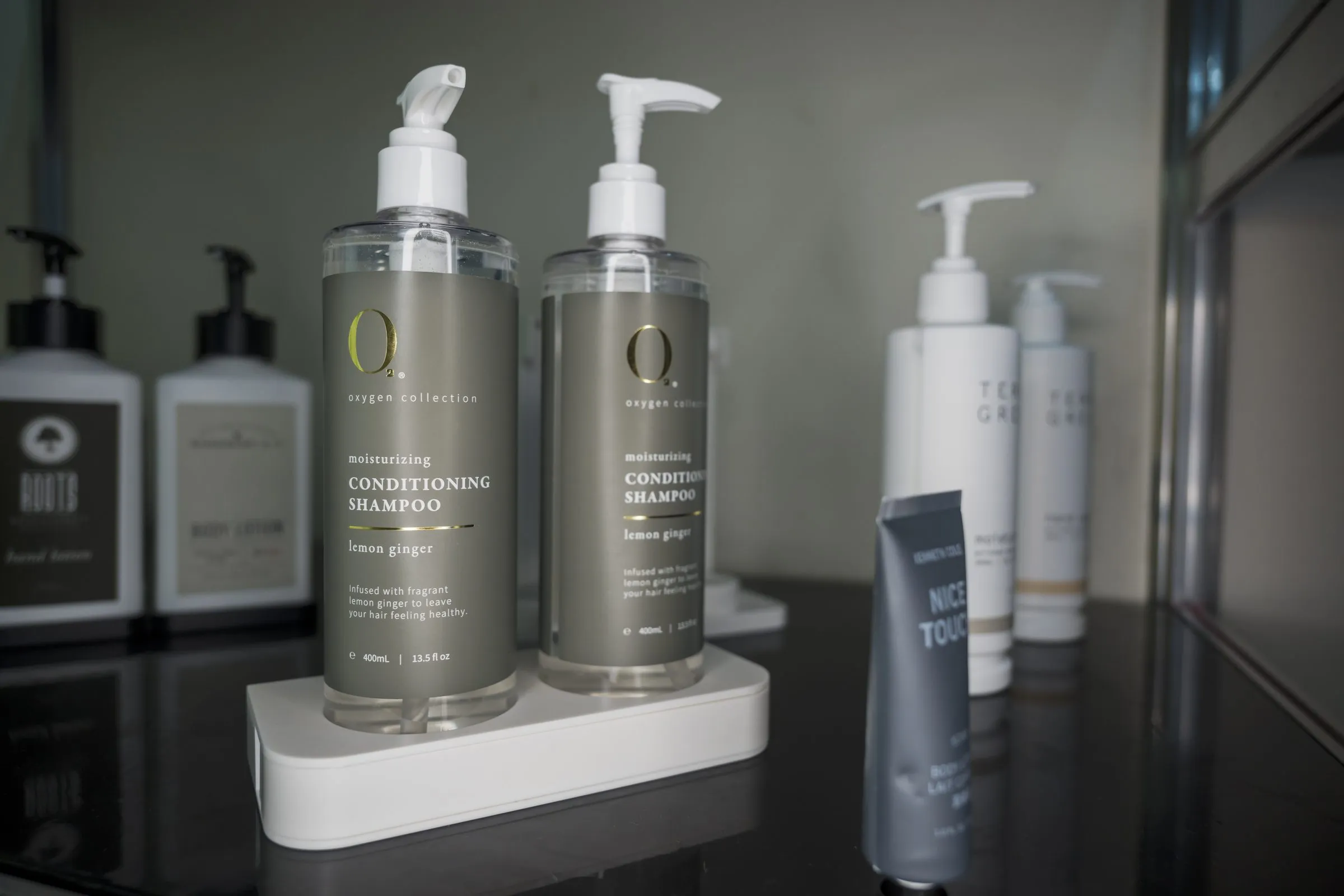 Dispensadores de shampoo y acondicionador instalados en contexto real de baño de hotel