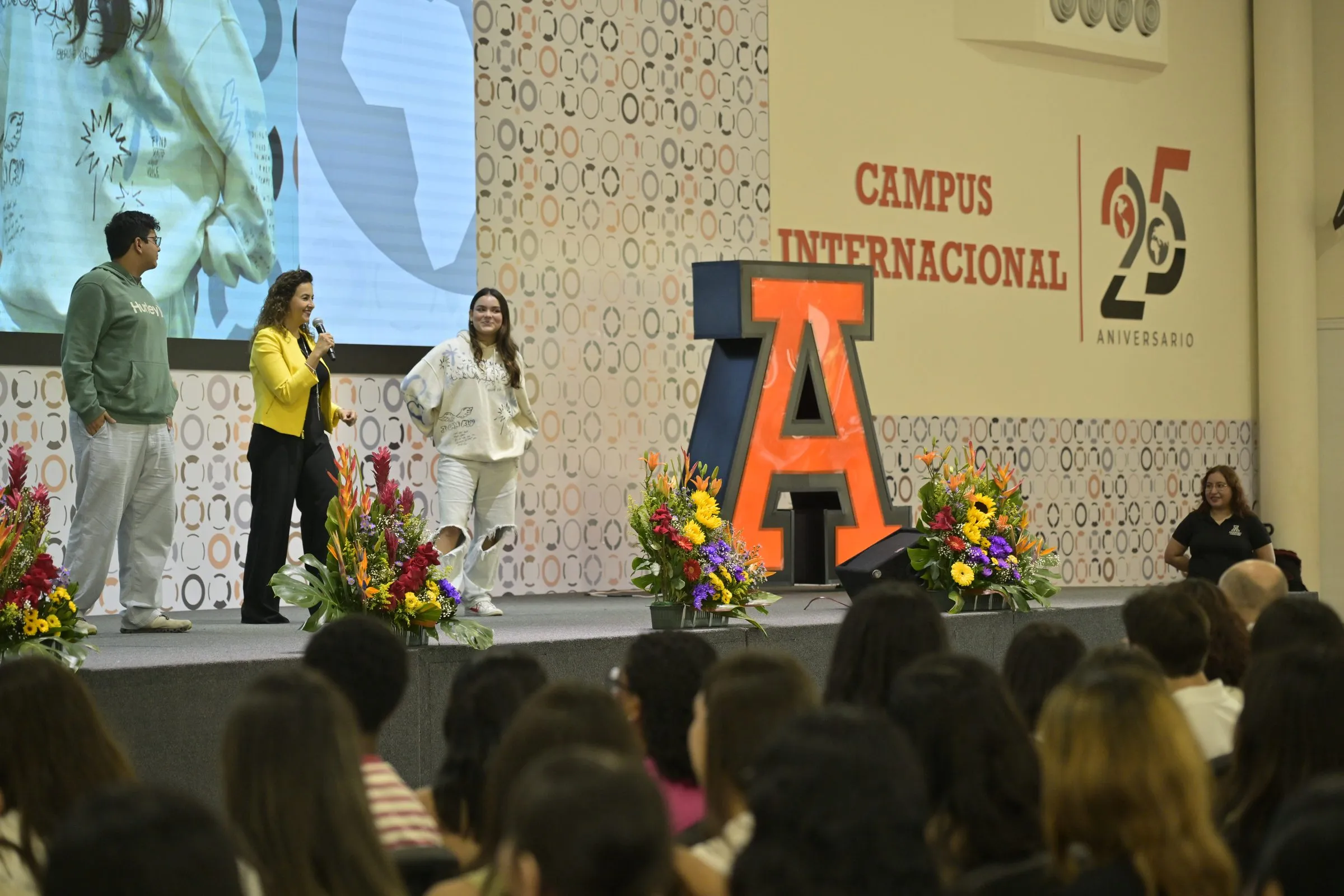 Escenario con host y pantalla de branding institucional, ejemplo de cobertura de día completo