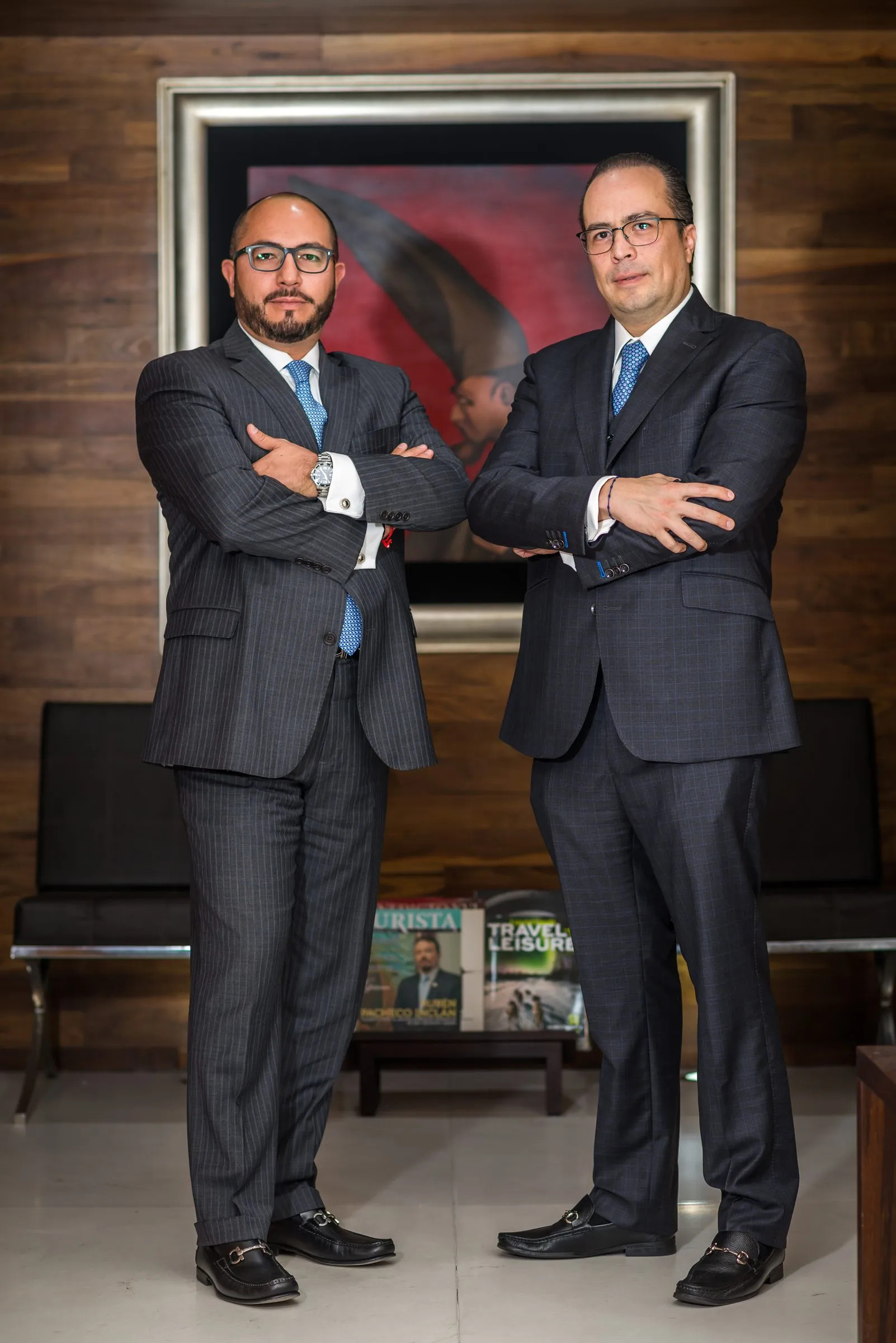 Dos retratados de pie frente a una obra de arte, encuadre y pose con dirección de arte definida para una sesión editorial