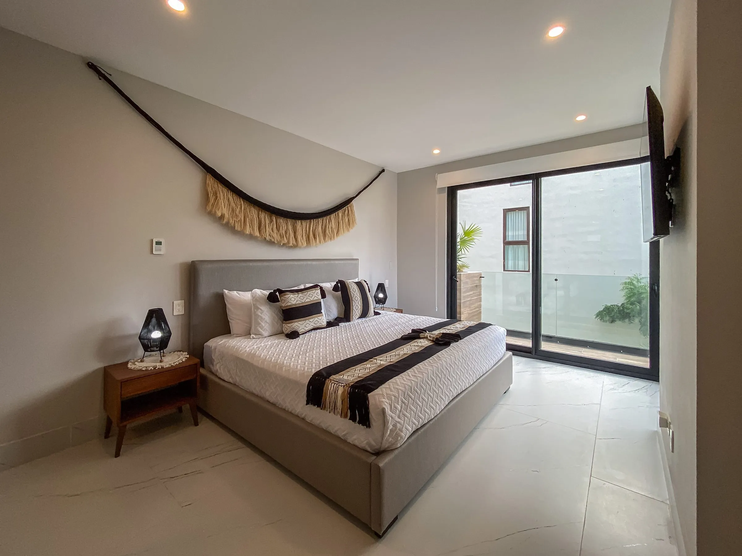 Bedroom styled with woven wall decor, feeling lived-in and inviting, not staged or empty