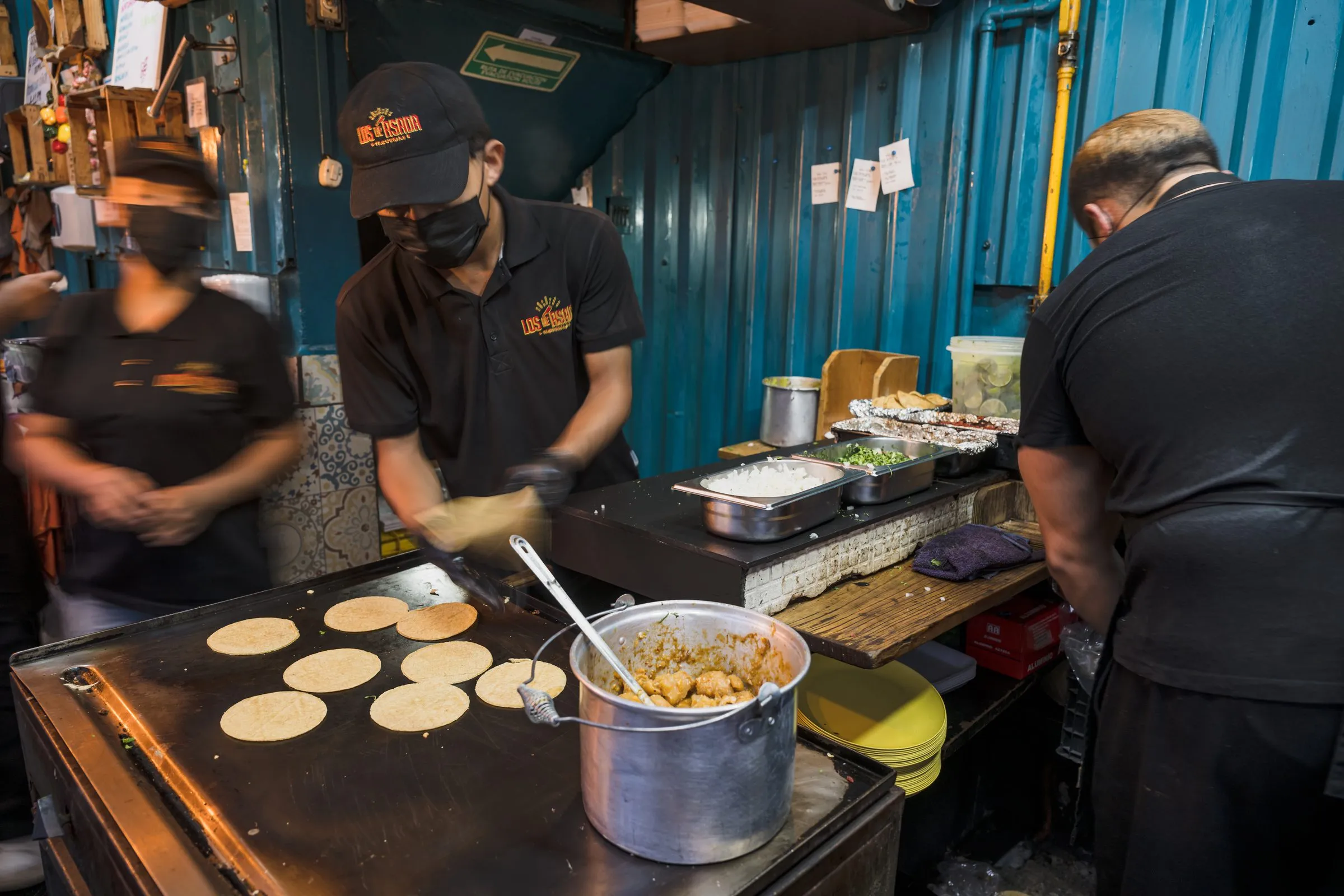 Manos del equipo de cocina trabajando el comal, armando tortillas y platillos en plena hora de servicio