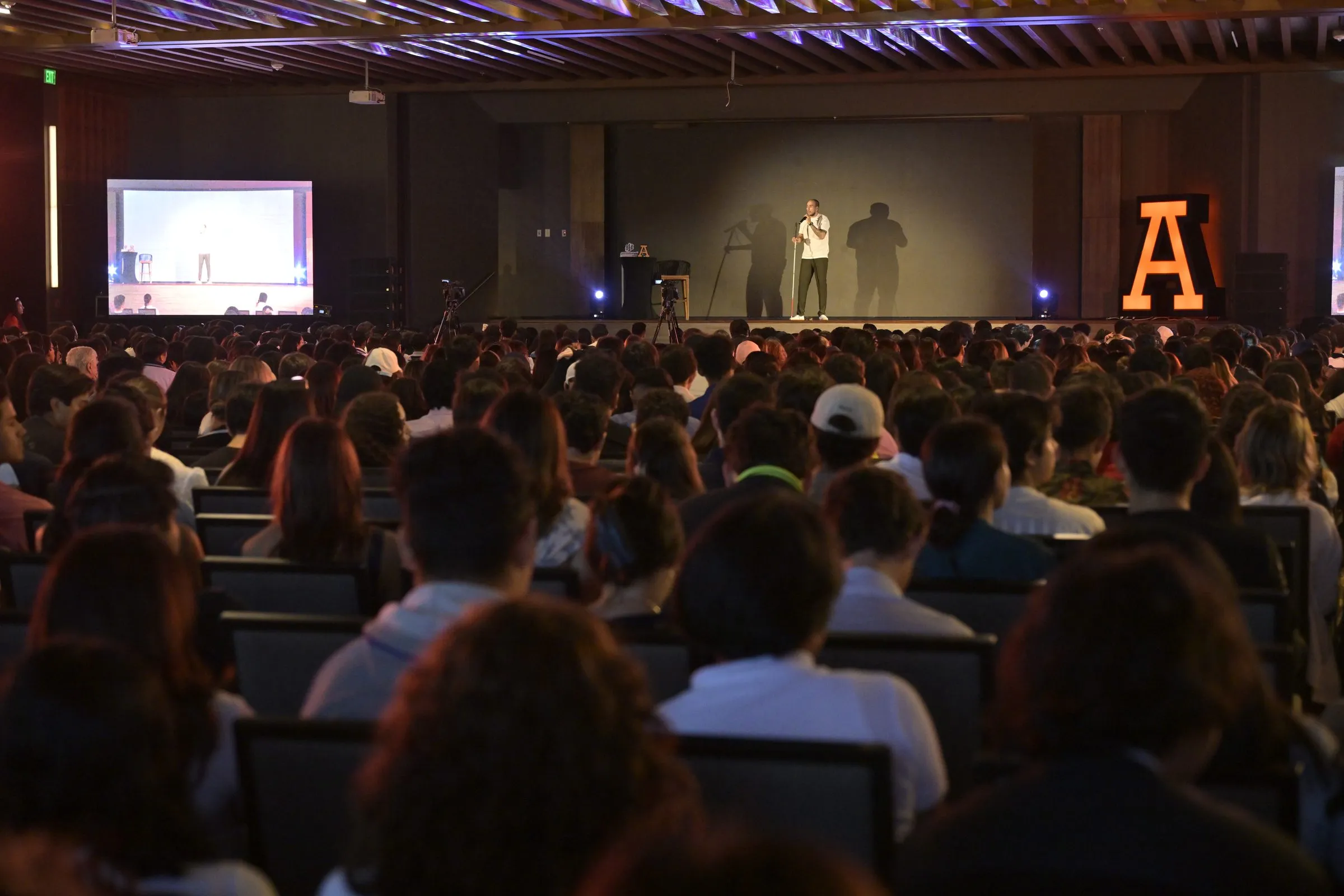 Escenario visto desde el fondo del salón, mostrando la escala y asistencia completa del evento