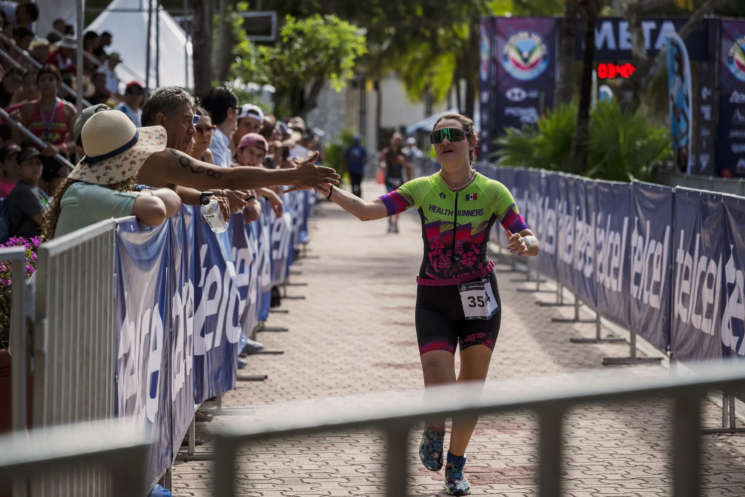 Atleta cruzando la meta con número de corredor visible, identificable para encontrar su propia foto después del evento