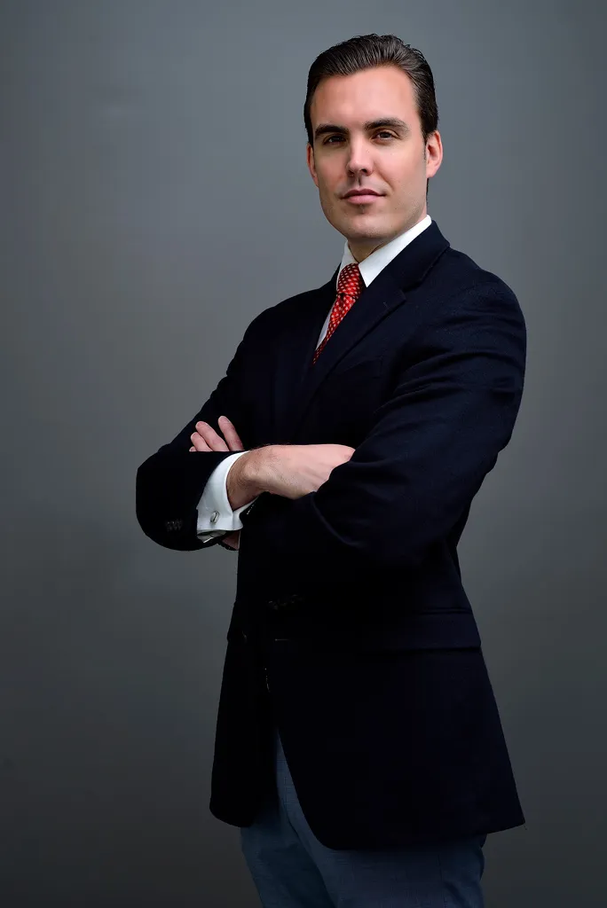 Retrato corporativo de un ejecutivo de traje oscuro y corbata roja con brazos cruzados