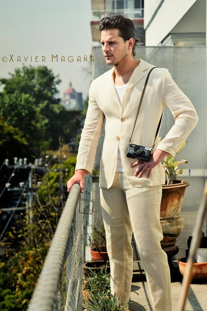 Hombre con traje claro y cámara al hombro, retrato de marca personal en exterior