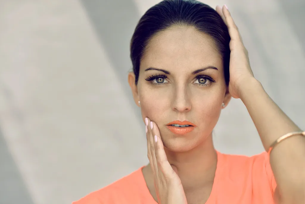 Retrato de estudio de una mujer con blusa color durazno y mirada directa