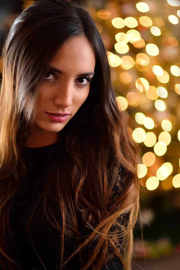Retrato de una mujer de cabello largo con luces desenfocadas de fondo