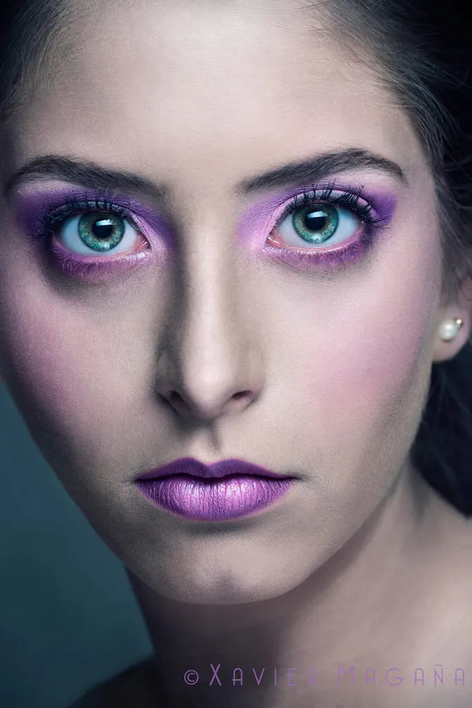 Retrato de belleza de una mujer con maquillaje en tonos violeta y mirada frontal