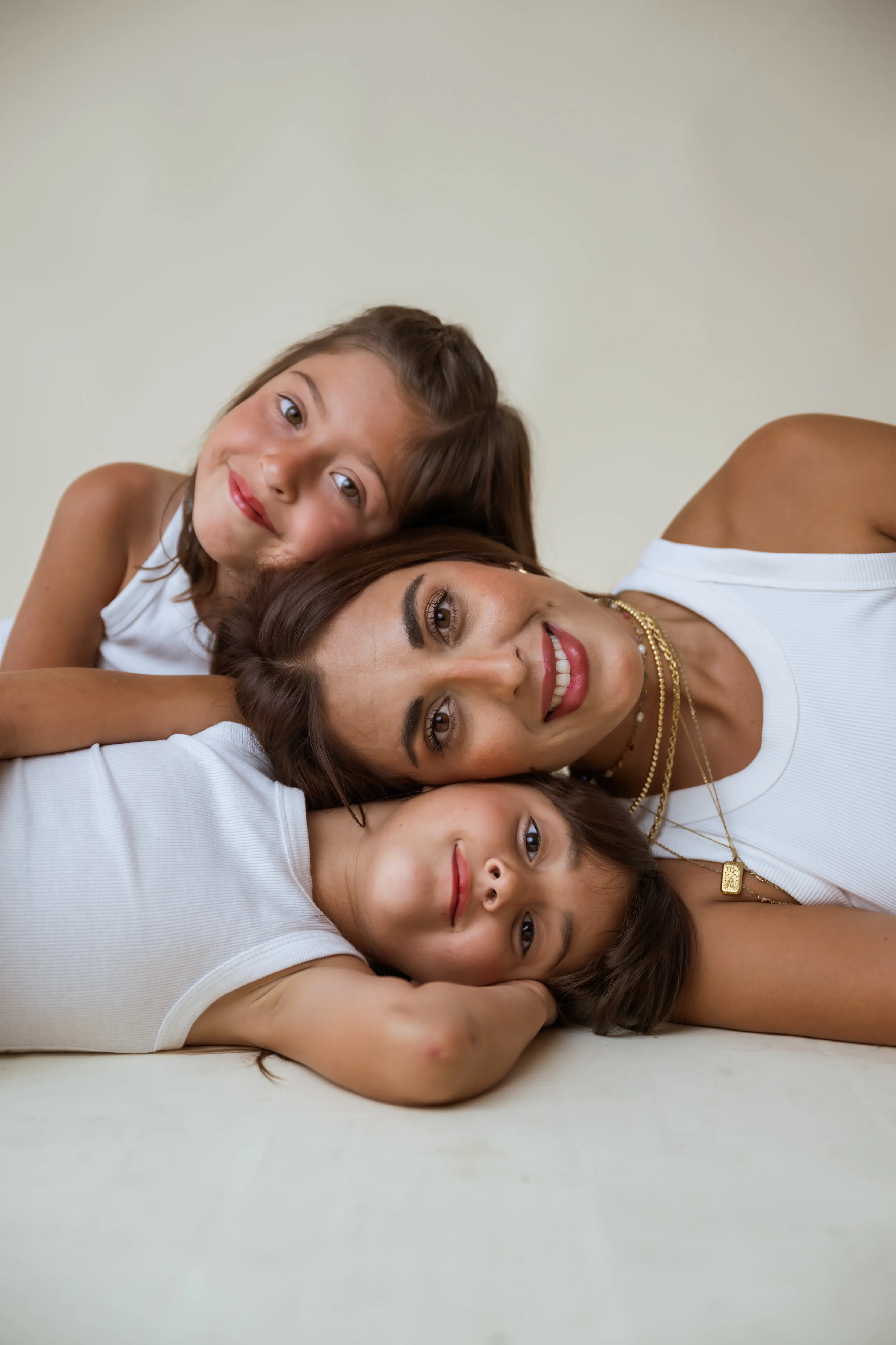 Mamá recostada con sus dos hijas, los tres rostros juntos formando un triángulo