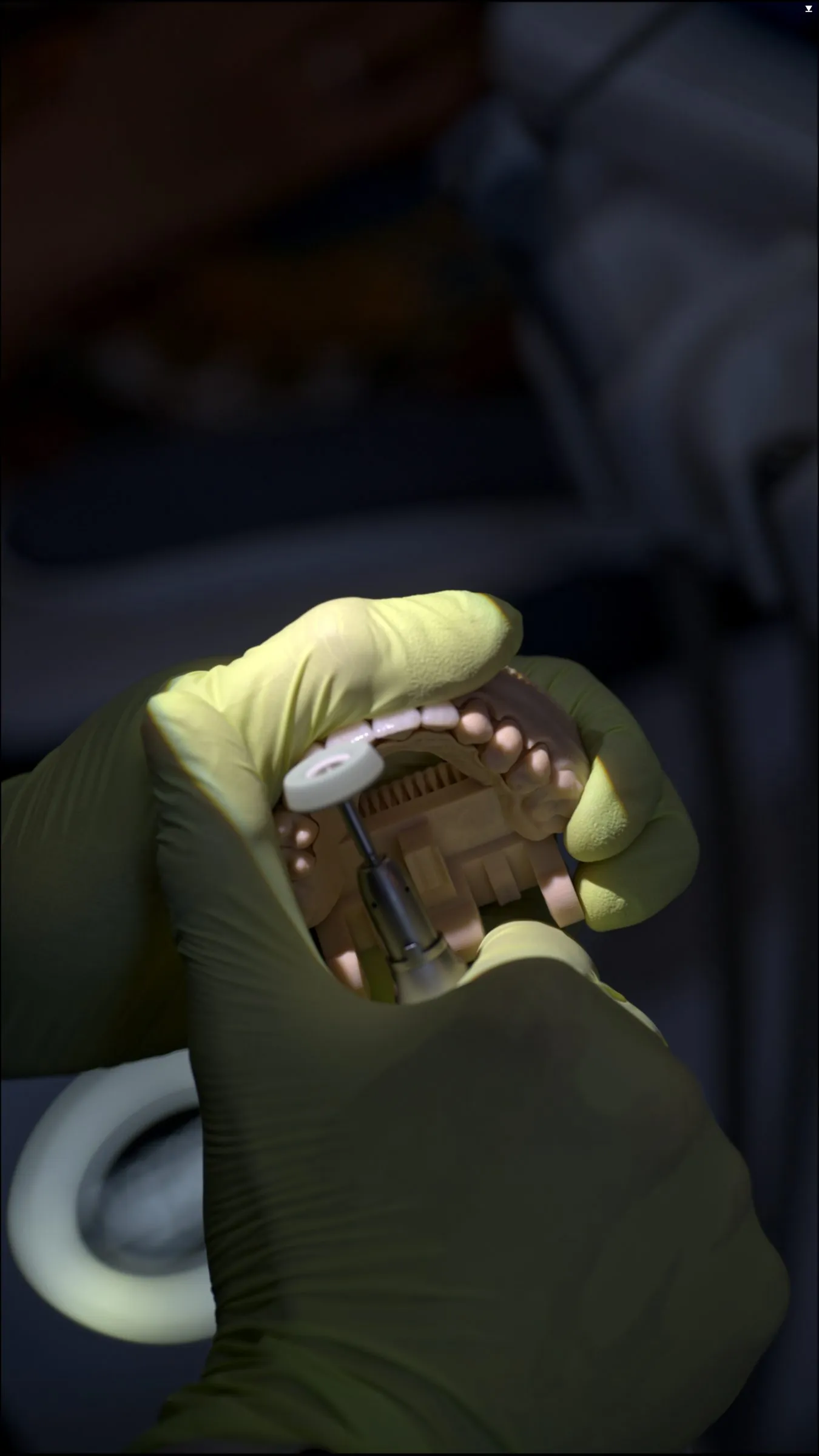 Manos enguantadas sostienen un modelo de arcada dental con piezas protésicas mientras una herramienta toca una de ellas, con el fondo desenfocado.