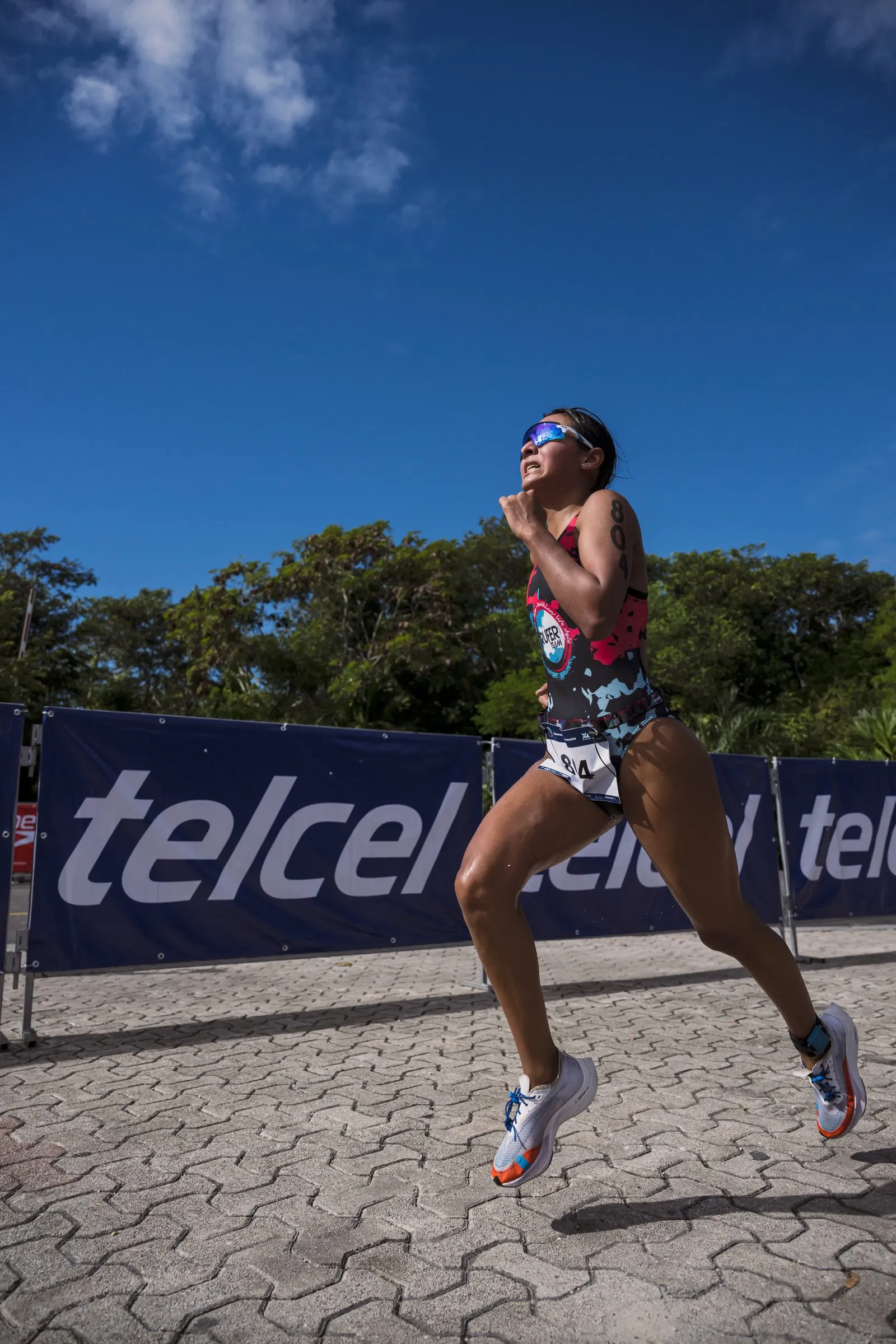 Atleta corriendo junto a un muro de anuncios de Telcel, patrocinador del evento, cerca de la meta del triatlón