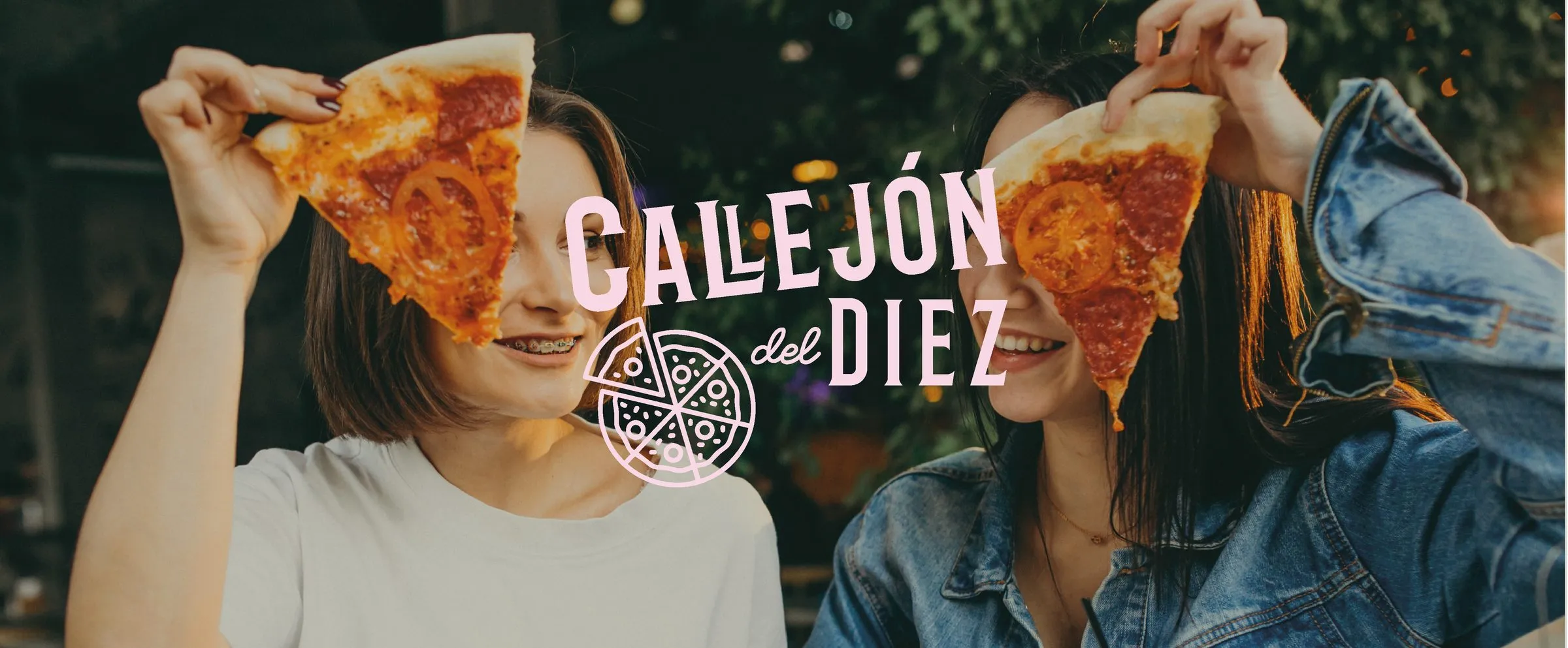 Two young women hold up pizza slices in front of their faces and smile at each other, with the brand logo overlaid between them