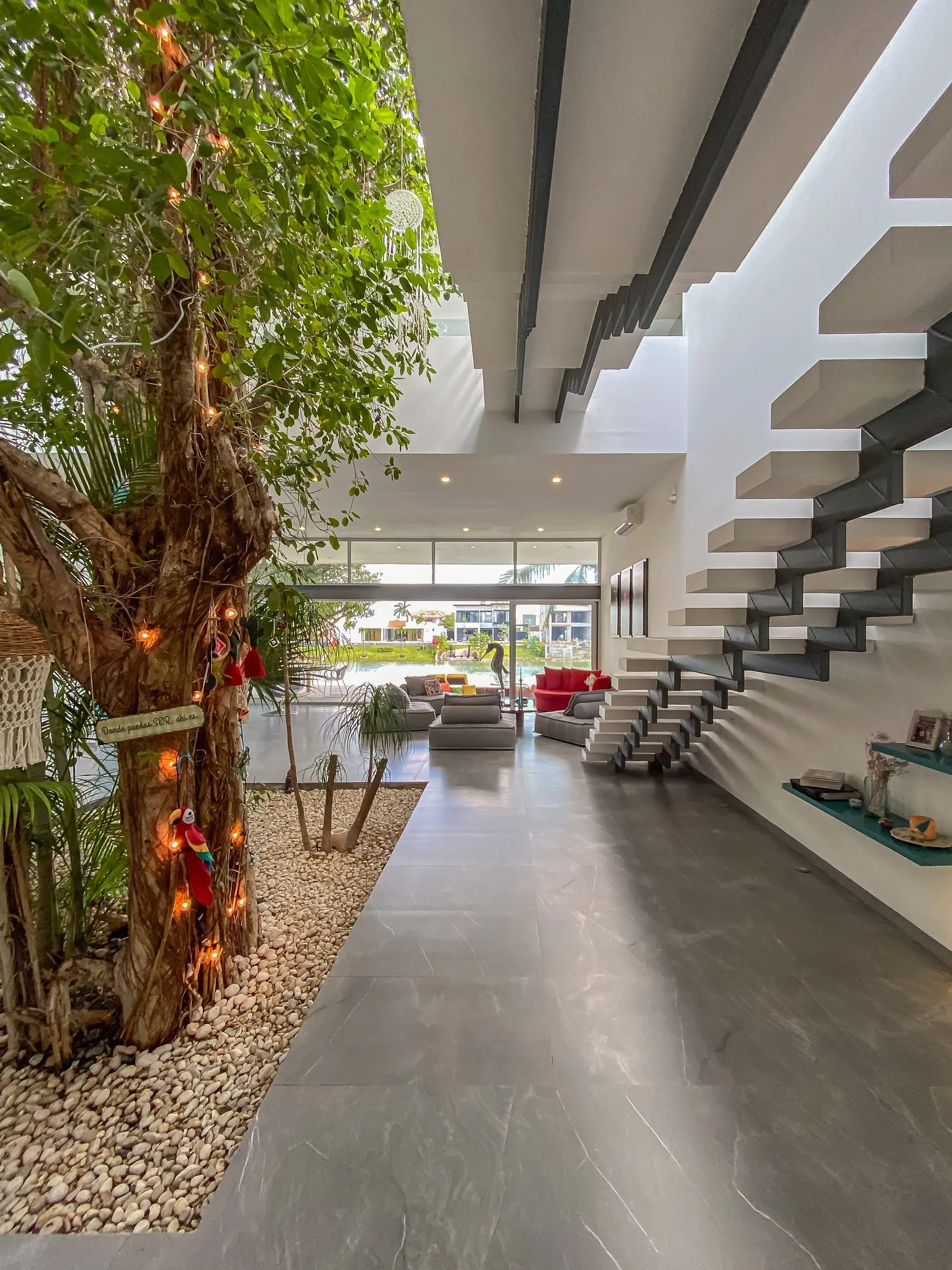 Entrada interior con árbol y escalera flotante de una propiedad premium en Cancún o la Riviera Maya, el gancho de un recorrido en video