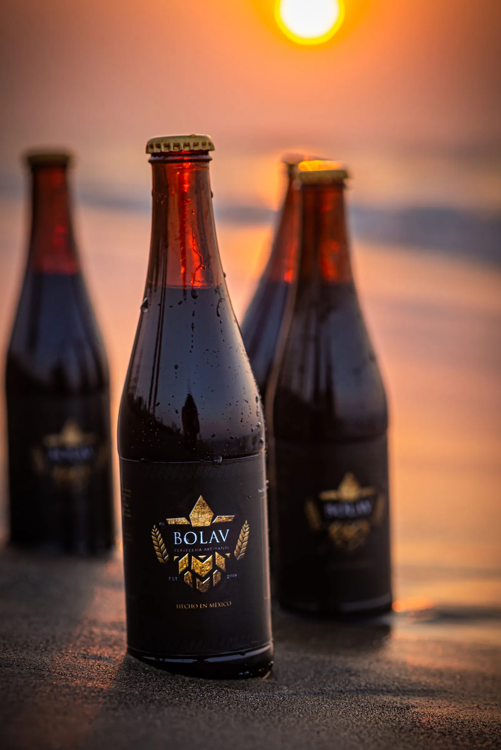 Botellas de cerveza Bolav con condensación real a contraluz de atardecer, fotografía de producto para etiqueta y marca