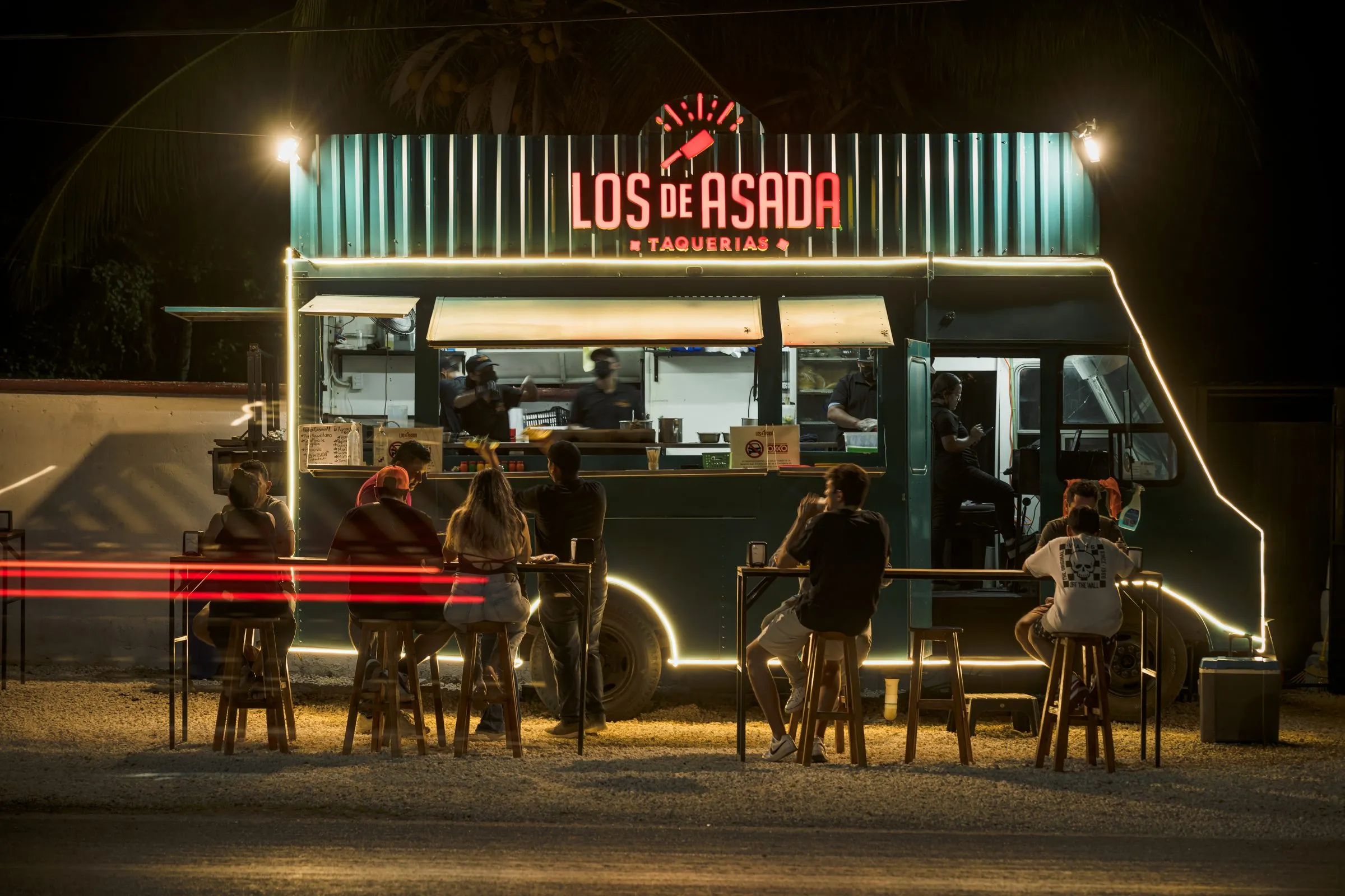 Food truck de taquería iluminado de noche con clientes en la barra, ejemplo de foto de portada para ficha de Google Business Profile