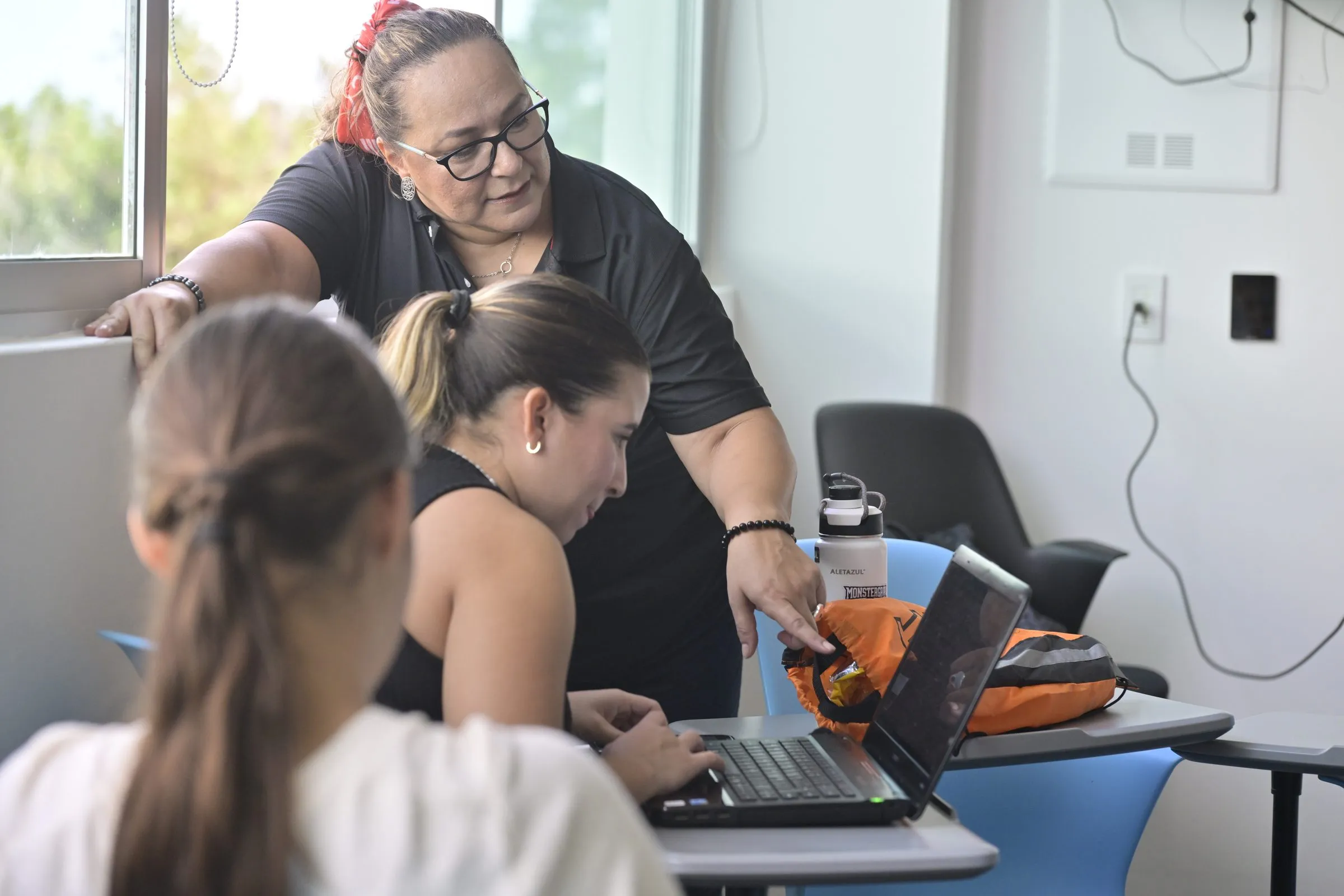 Dos personas revisando material en laptop con equipo de cámara sobre la mesa, edición en sitio durante un evento