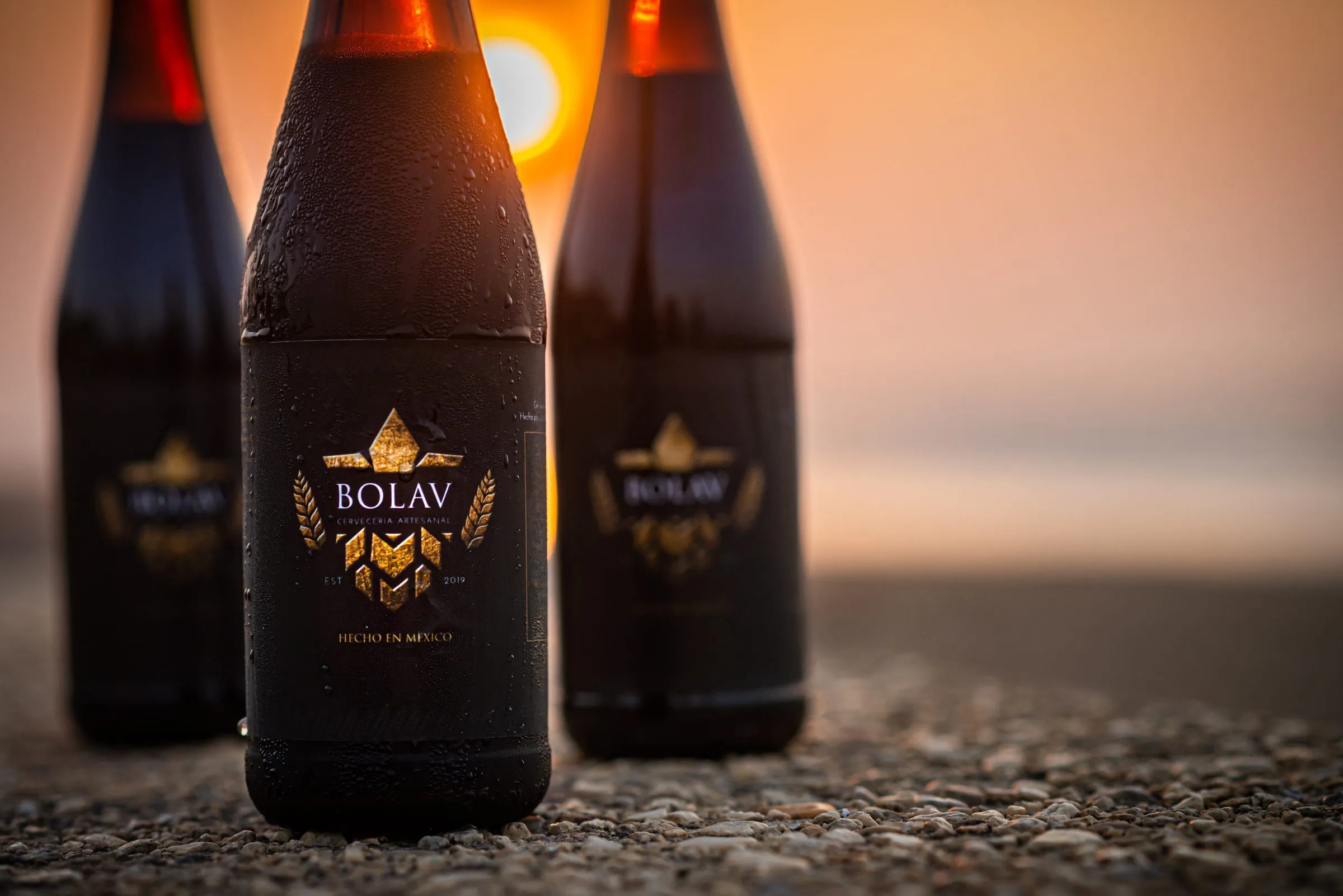 Fotografía de producto de cerveza artesanal en la playa al atardecer